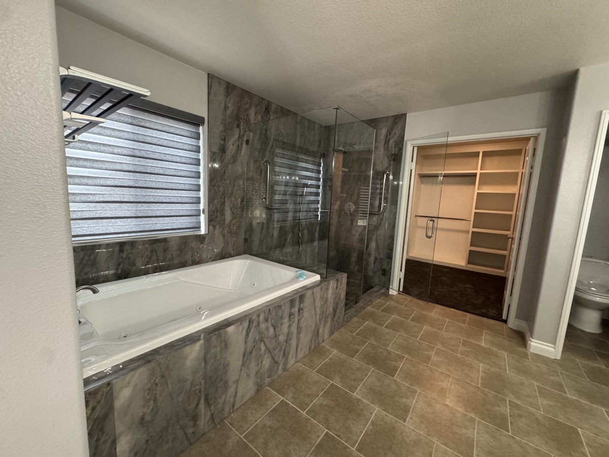 Gray marble master bath with jetted tub and glass shower